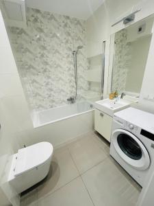 a bathroom with a toilet sink and a washing machine at Apartament Arena Gdynia in Gdynia
