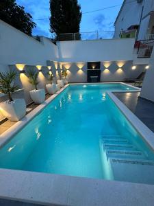 een zwembad met verlichting aan de zijkant van een huis bij Apartments Imperium in Trogir