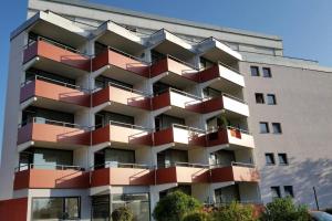 ein großes Apartmenthaus mit roten Balkonen darauf in der Unterkunft Wohnung mit Teil See Sicht und Schwimmbad in Uhldingen-Mühlhofen