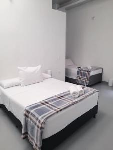 two beds in a room with white walls at Aloja-T en Apartamento amoblado 6 con balcón Ciudad Bolivar in Ciudad Bolívar