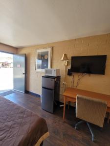 Habitación de hotel con cama, escritorio y TV. en Westerner Motel, en Williams