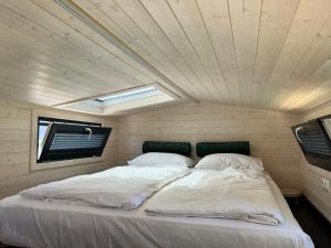 a large bed in a small room with a ceiling at Tiny House Lovely Sunshine in Giethoorn