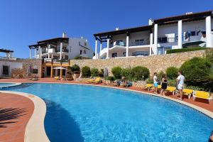 a group of people standing around a swimming pool at Paddle - Sea view apartment with 3 pools, tennis & squash court in São Martinho do Porto