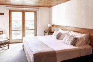 Un dormitorio con una gran cama blanca y una ventana en Departamento Hosteria del Cerro en San Carlos de Bariloche
