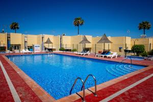 ein großer Swimmingpool mit Stühlen und Palmen in der Unterkunft Bungalow Costa Adeje El Cortijo 2-9 in Playa de las Americas