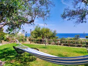 a hammock in a field with the ocean in the background at Tende Glamping Vista Mare Marina Serra in Marina Serra