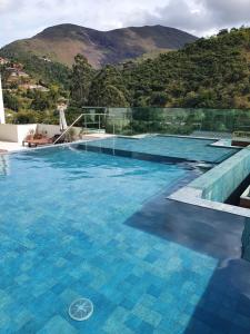 una piscina con una montaña en el fondo en Cobertura Piemonte, en Itaipava