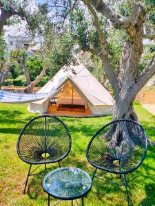 three chairs and a tent in the grass at La Nuova Tenda di Casa Camilla Journey in Marina Serra