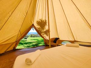 a bed in a tent with a view of a field at Tende Glamping Vista Mare Marina Serra in Marina Serra