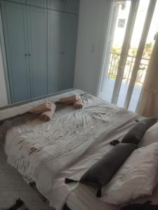 een bed met kussens in een kamer met een raam bij Bee life apts, Sweet house in Kókkinos Pírgos