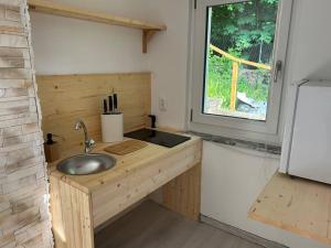 Elle comprend une petite cuisine avec un évier et une fenêtre. dans l'établissement Ferienhaus Lavendel, à Obergurig