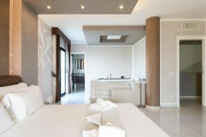a bedroom with a white bed and a kitchen at Geovillage Green Residence in Olbia