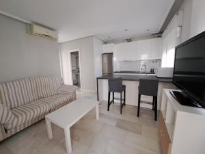 cocina y sala de estar con sofá y mesa en Apartamento Pinares del atlantico, en Chiclana de la Frontera