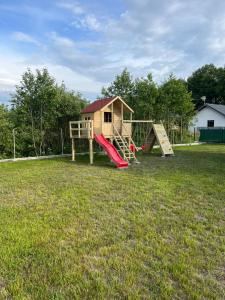 a playground with a slide and a play house at Domki Niedźwiadki nad morzem in Kopalino