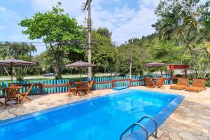 a swimming pool with chairs and tables and umbrellas at Pousada Sanremo Inn in Ubatuba