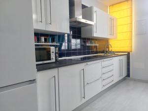 a white kitchen with white cabinets and a microwave at La Palma in Tarajalejo