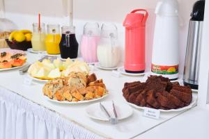 a table filled with different types of pastries and drinks at Pousada Sanremo Inn in Ubatuba