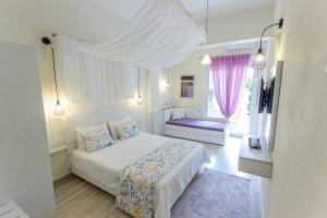 a white bedroom with a bed and a window at Ilion Luxury Studios & Apartments in Asprovalta