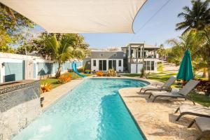 una piscina con sillas y una casa en Ocean Front Villa, 2 Private Pools, BBQ, Tennis court and more!, en Vega Baja
