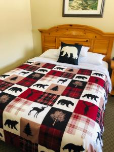 a bed with a checkered quilt with animals on it at Parkway Motel in Wawa