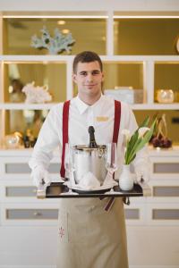a man in a kitchen holding a tray with a mixer at Boutique Hotel Vissi d'Arte in Budva