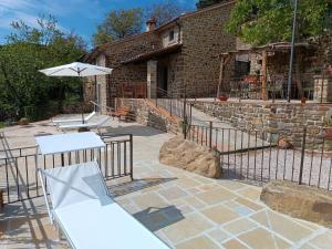 een patio met 2 tafels en een parasol bij Rustico Toscano in Castel Focognano