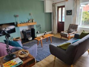 a living room with a couch and a table at Cheerful two bedroom cottage in the Forest of Dean in Lydbrook