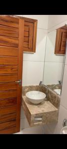 a bathroom with a white sink and a wooden cabinet at Vila Alicia Flecheiras in Flecheiras