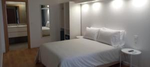 1 dormitorio con cama blanca y espejo en Naturalis, en Vila Nova de Milfontes