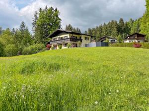 a house on a hill with a field of grass at Am Randersberg - Wohnung Nr 1 in Grossgmain