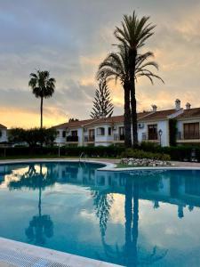 una piscina con palmeras frente a una casa en APARTAMENTO VERA COAST 123, en Playas de Vera