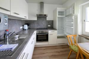 uma cozinha com armários brancos e um lavatório em Am Randersberg - Wohnung Nr 1 em Grossgmain