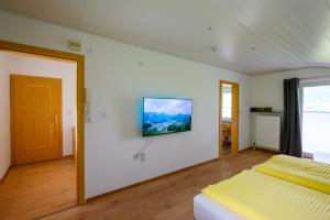 um quarto com uma cama e uma televisão na parede em Am Randersberg - Wohnung Nr 1 em Grossgmain