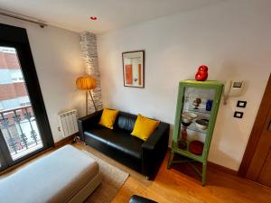 a living room with a black couch and a refrigerator at Lotila Flats Cabañaquinta in Aller