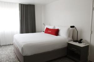 a hotel room with a white bed with a red pillow at Vinland Hotel and Lounge in Solvang