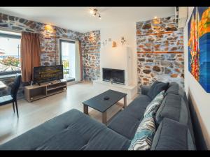 a living room with a couch and a stone wall at DreamStone Residence in Skala Prinou