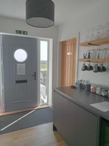 a kitchen with a grey door and a counter top at Flotnar Hús - Ensuite Rooms in Keiss