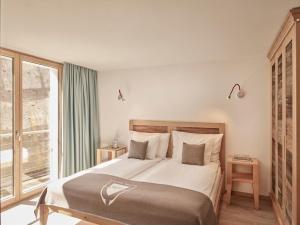 a bedroom with a large bed and a large window at Firefly Luxury Suites in Zermatt
