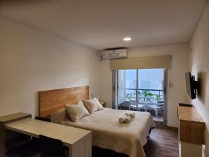 a bedroom with a bed and a table and a balcony at Aires Verdes de Capital Depto in Salta