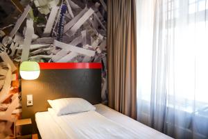 um pequeno quarto com uma cama e uma janela em Comfort Hotel Norrköping em Norrköping