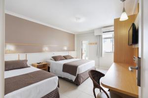 a hotel room with two beds and a television at Miramar Hotel in Balneário Camboriú