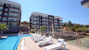 a swimming pool with lounge chairs next to a building at Spacious Flat at the Beach Pool, huge Balcony, 2 Bedroom in Alanya