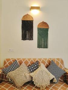 a couch with pillows and two knick knacks on the wall at Boho Suite by Hey Studios in Ghaziabad