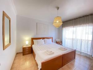 a bedroom with a large bed and a window at Aloha Burgau Guesthouse in Burgau