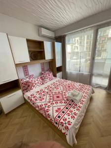 a bedroom with a bed with a red and white blanket at Studio Shevitsa & free Garage in Veliko Tŭrnovo
