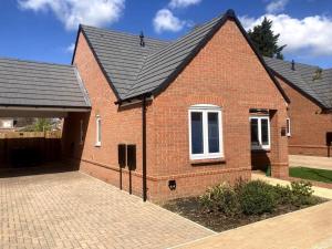 a red brick house with a black roof at Robins Nest Luxury Bungalow in Northampton