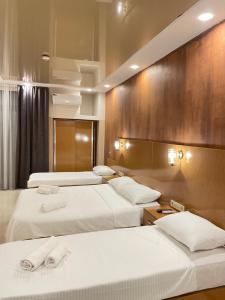 um quarto de hotel com três camas com lençóis brancos em New House Kobuleti 2 em Kobuleti