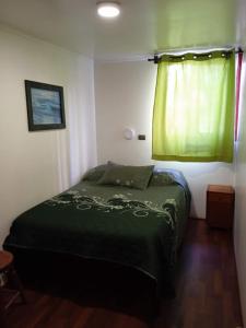 Un dormitorio con una cama verde y una ventana. en Residencial la Cabaña, en Santiago