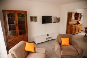 a living room with two chairs and a flat screen tv at Apartmani Romić R in Novi Travnik