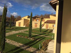a house with trees in front of a yard at Appartamento - La Vinaccia in Montepulciano